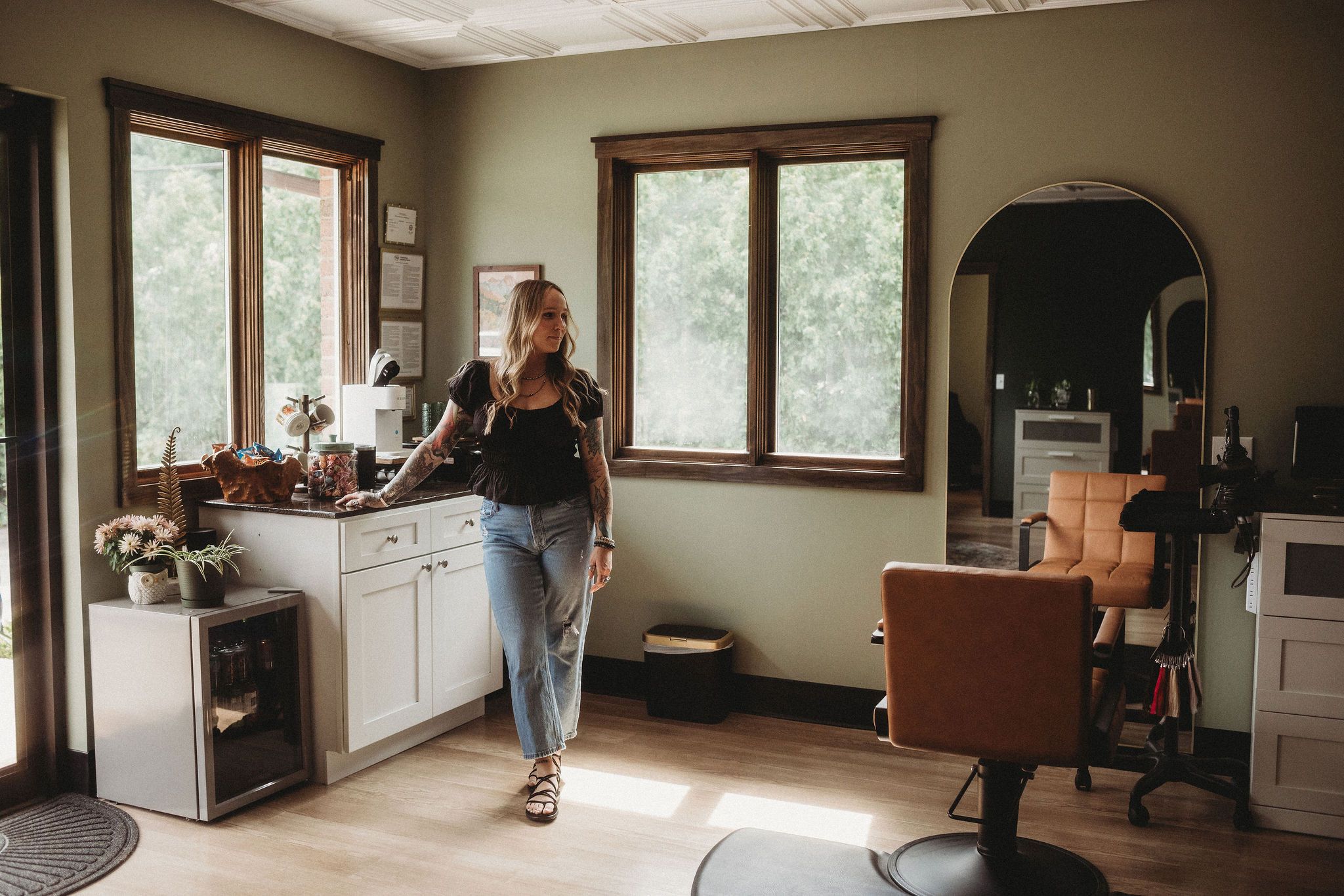 Olivia, owner of Everfern Hair Collective, standing in her sunlit suite beside a tan styling chair